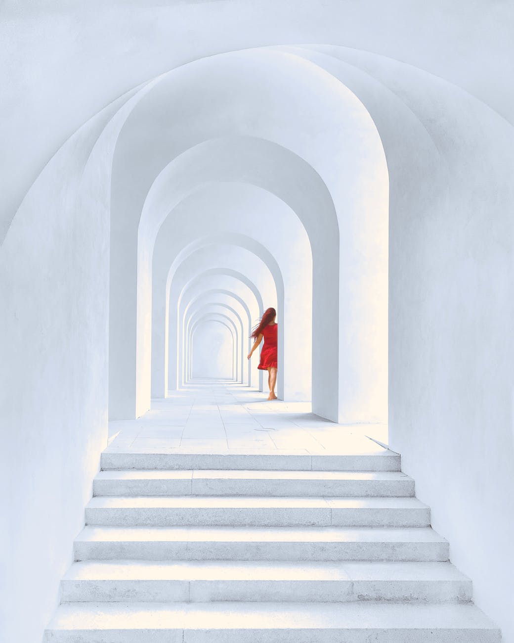 woman in red dress standing in white arch building